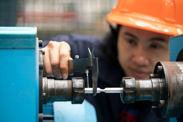 junge asiatische ingenieurin, die vernier für die messung des prüfstücks auf der maschine - mikrometer feinmessgerät stock-fotos und bilder