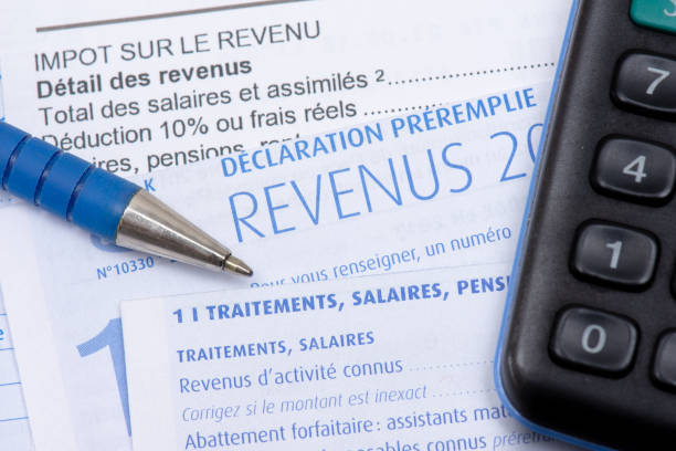 French income tax return French pre-filled income tax return with the page about income from salaries, treatments, pensions and annuities, along with a pen and a calculator french language photos stock pictures, royalty-free photos & images
