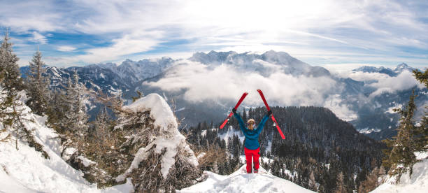 les femmes retenant ses skis de ski de randonnée dans l’air-journée ensoleillée d’hiver dans les alpes - skiing sports helmet powder snow ski goggles photos et images de collection