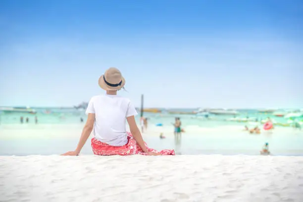 Photo of Cute woman tourist sitting on sand beach of Pattaya sea island in Thailand on summer holidays on green sea and blue sky background