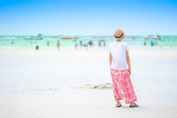 Photo of Cute woman tourist sitting on sand beach of Pattaya sea island in Thailand on summer holidays on green sea and blue sky background