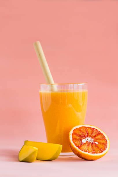 istock Mango and orange smoothie in glass on pink background. 1139510361