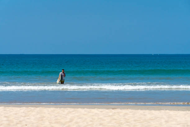 istock Young man with surfboard exiting the sea on Pakarang Beach 1139510366