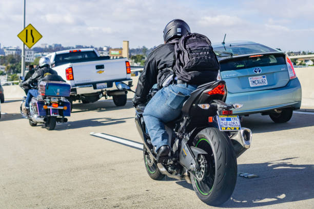 motocyclistes conduisant à travers la circulation lourde - motorcycle biker sport city photos et images de collection