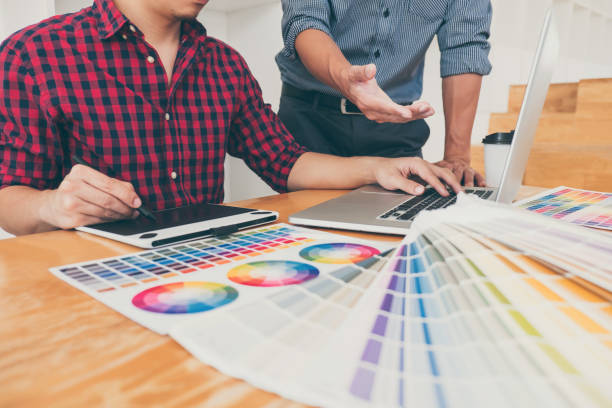 istock Teamwork of young creative designers working on project together and choose color swatch samples for selection coloring on digital graphic tablet at workspace 1139526906