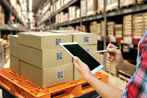 Industrial 4.0 , Augmented reality and smart logistic concept. Hand holding tablet with AR application for check order pick time around the world and supply chain in smart factory background.