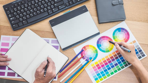 istock Two colleagues creative graphic designer working on color selection and drawing on graphics tablet at workplace, Color swatch samples chart for selection coloring 1139534593