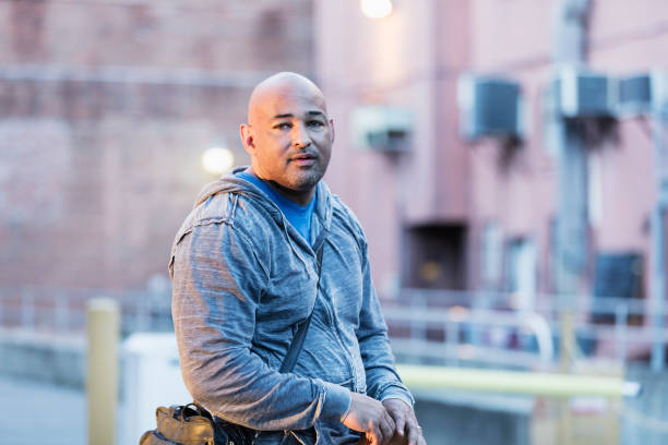 istock Hispanic man with shaved head standing in urban area 1139538537