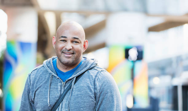 istock Hispanic man with shaved head standing in city, smiling 1139539225