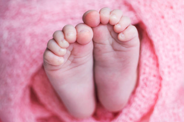 The baby's feet are on the bed, sleeping soundly.