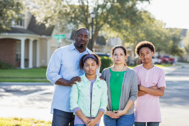 Serious Interracial family in residential community An interracial Hispanic and African-American family with two children standing together in a residential neighborhood. The father is African-American and mother is Hispanic, both in their 40s. Their daughter is 11 years old and her brother is 14. They have serious expressions on their faces, looking annoyed or a little angry. irritation photos stock pictures, royalty-free photos & images
