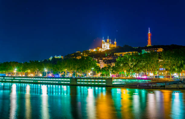 illuminierte basilika notre dame de fourvière hinter dem fluss saone in lyon, frankreich - basilika notre dame de fourvière stock-fotos und bilder