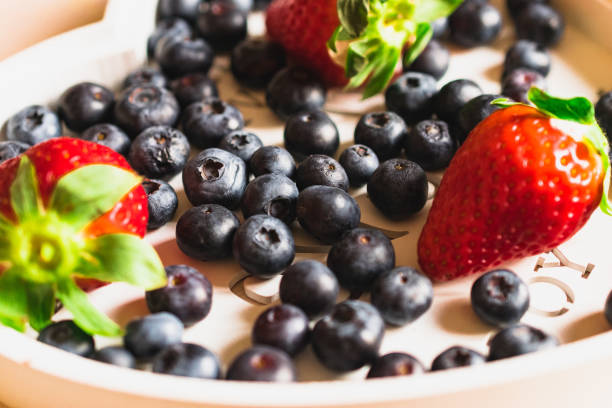 Composition of strawberry and blueberry on light background. Sunshine day light.