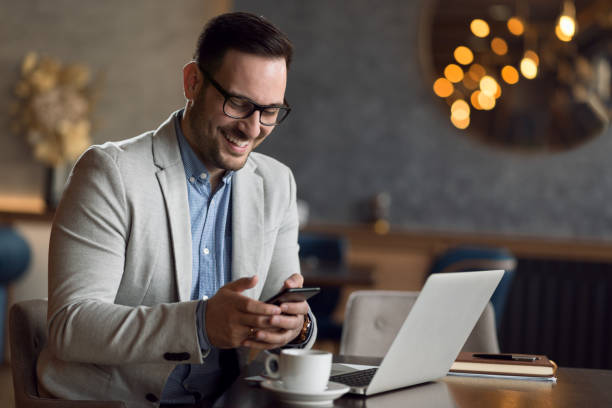 istock Young businessman in a cafe using cell phone and laptop 1139551607