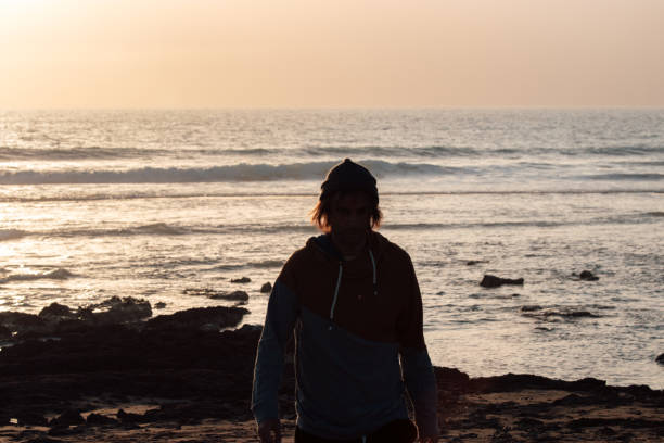 istock Man in beanie hat on the beach at sunset 1139553819