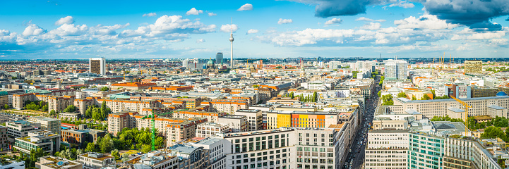 Big blue skies and fluffy clouds over an aerial panoramic vista above the rooftops of Berlin, Germany’s vibrant capital city.