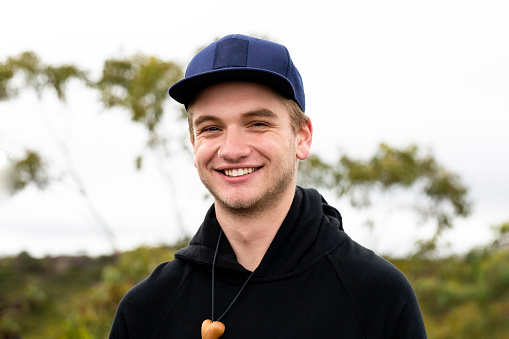 Portrait of smiling handsome young man with cap, background with copy space, full frame horizontal composition