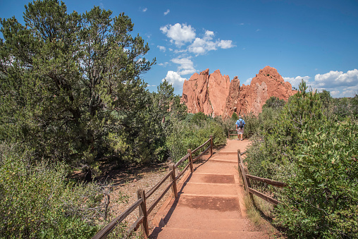 Man walking on the trail on mountain trip in Utah. Stairs to North Window Arch on the Windows Loop Trail. Arches National Park, Utah, USA