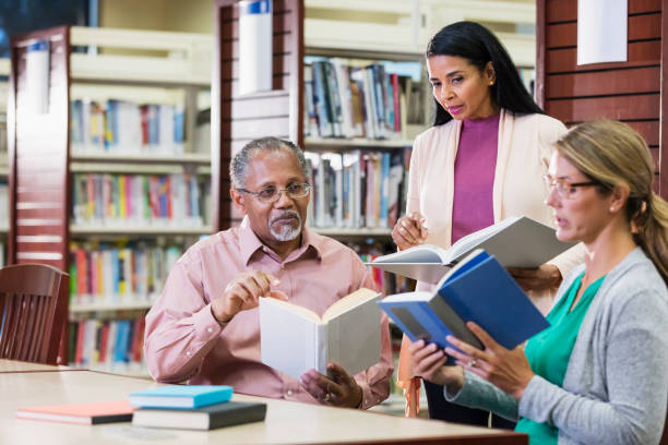 istock Group of three multi-ethnic adults reading, talking in library 1139566187