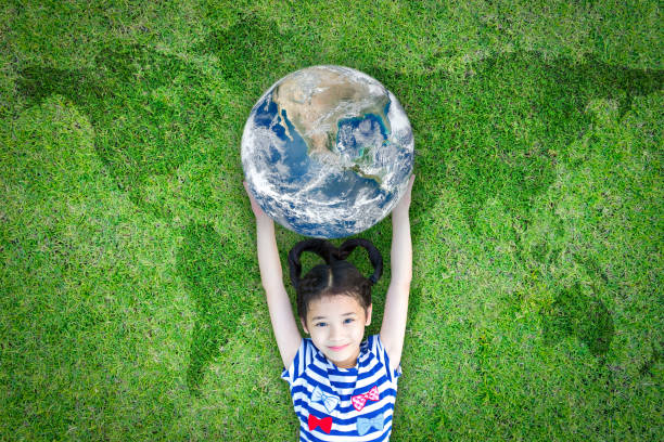 dzień ziemi, ekologiczna i społeczna koncepcja odpowiedzialności społecznej z dzieckiem podnoszącym świat na zielonym trawniku: element obrazu umeblowanego przez nasa - environment child earth green zdjęcia i obrazy z banku zdjęć