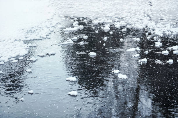 istock Ice on frozen pond with small patches of snow crystals, tree reflection on surface 1139567524
