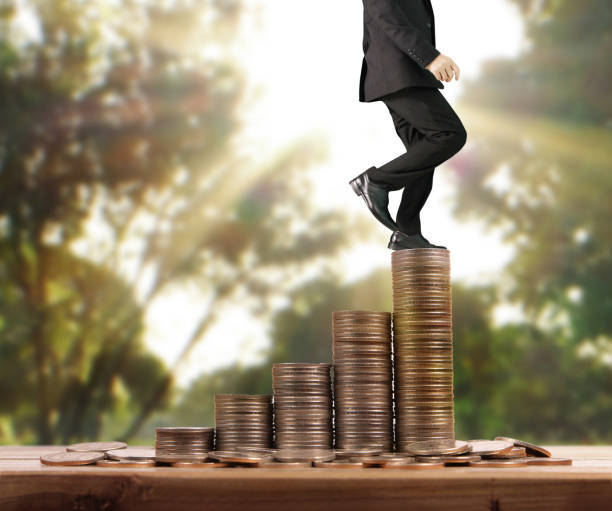 istock Businessman walk on stack of coins which grows success 1139579010