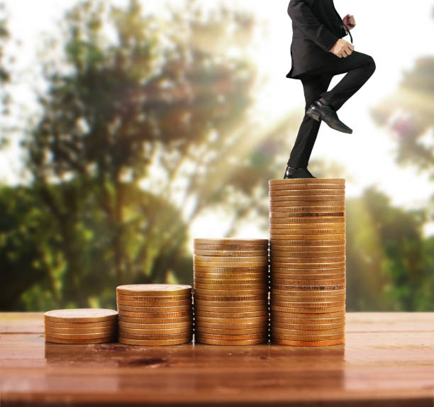 istock Businessman walk on stack of coins which grows success 1139579012