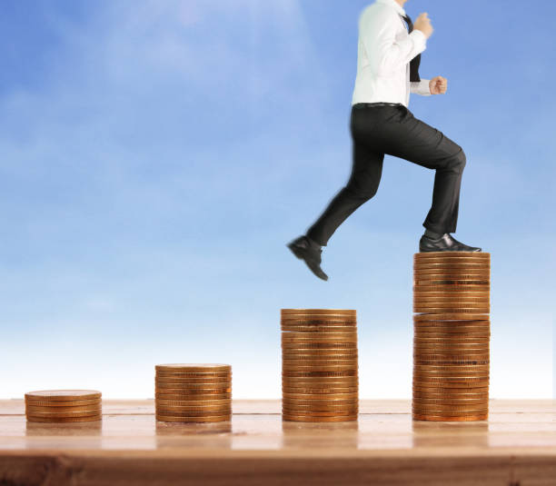 istock Businessman walk on stack of coins which grows success 1139579022