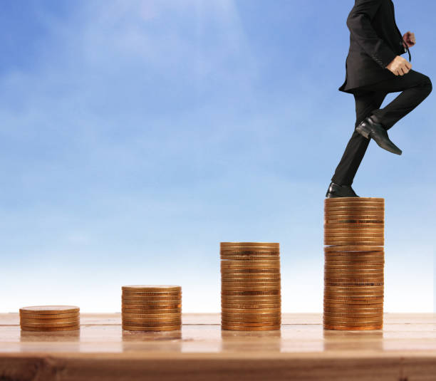 istock Businessman walk on stack of coins which grows success 1139579028