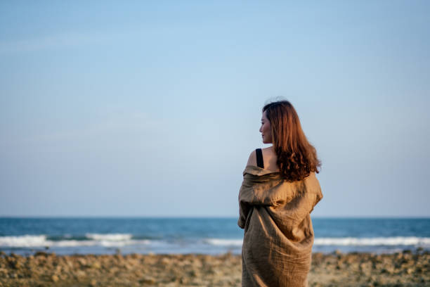 istock woman walking on the beach by the seashore 1139581129