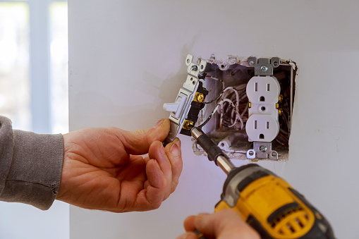Las manos de un electricista instalando un interruptor de encendido photo