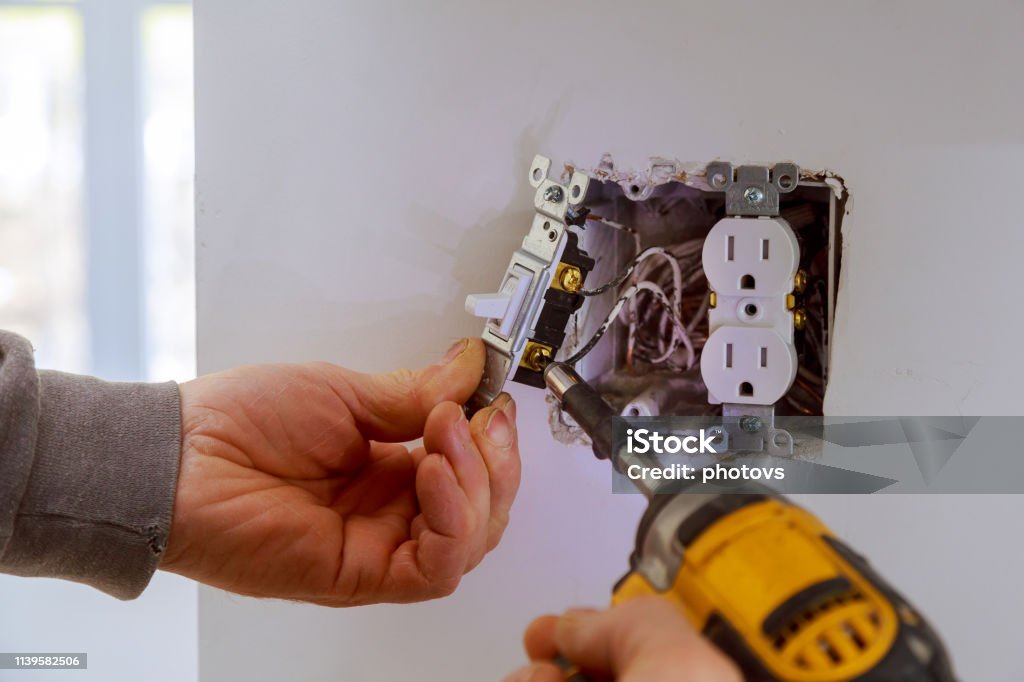 The hands of an electrician installing a power switch The hands of an electrician installing a power switch to the electrical junction box Electricity Stock Photo