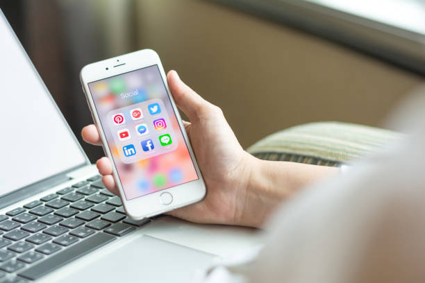 mujer de negocios sosteniendo smartphone iphone con iconos de las redes sociales en la pantalla como estilo de vida relajante, tecnología de internet en la vida cotidiana - iphone ipad apple computers business fotografías e imágenes de stock