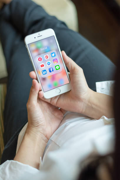 бизнес-женщина, держащая iphone смартфон с иконками социальных медиа на экране как расслабляющий образ жизни, интернет-технологии в повседнев - iphone google holding telephone стоковые фото и изображения