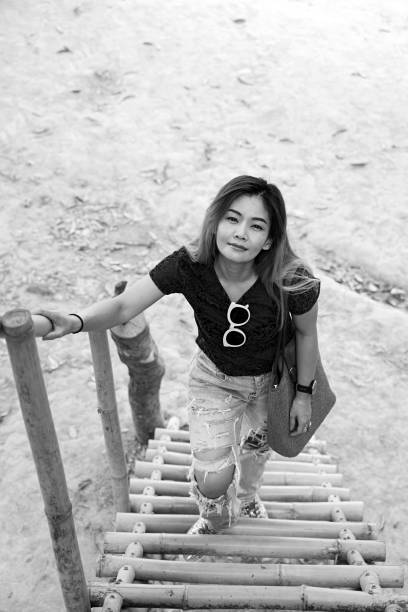 istock Asian woman smiling standing on bamboo stairs 1139586091