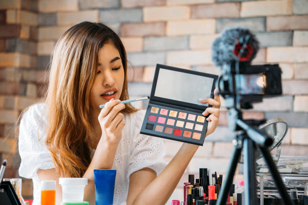 istock Pretty Asian woman recording makeup tutorial video about cosmetics with mobile phone on tripod 1139596785