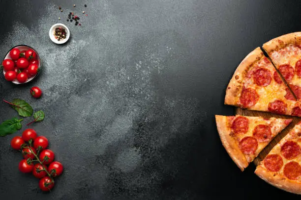 Pepperoni pizza on black slate background with copy space for text. Top view