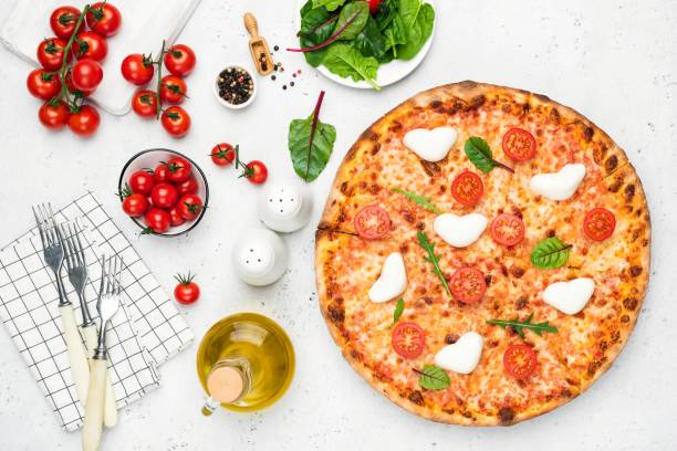 Italian pizza with heart shaped mozzarella, tomatoes and basil stock photo