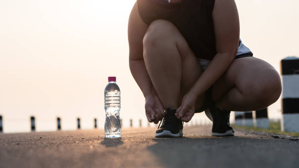 buty do biegania - zbliżenie kobiety wiążącej sznurowadła do butów. ona przygotowuje się do joggingu we wczesnych godzinach porannych światła słonecznego. pojęcie utraty wagi z ćwiczeń. z miejscem na kopiowanie. - shoe tying adult jogging zdjęcia i obrazy z banku zdjęć