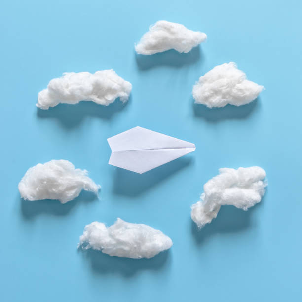istock Paper origami plane among white clouds on blue background. 1139601322