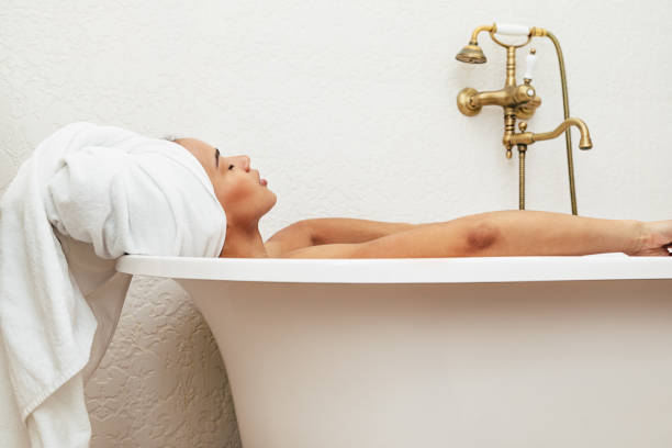 istock Woman in towel wrapped around head relaxing in bath 1139603528