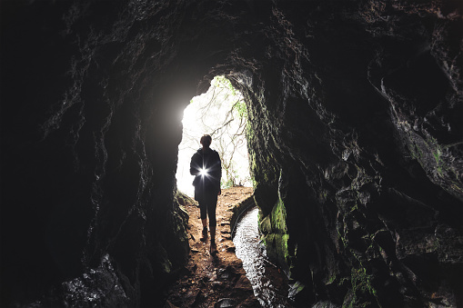 Leavda walk on Madeira island. Woman with flashlight entering the tunnel.