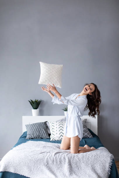 istock Happy woman having fun pillow throws enjoying funny activity on weekend at home. 1139605585