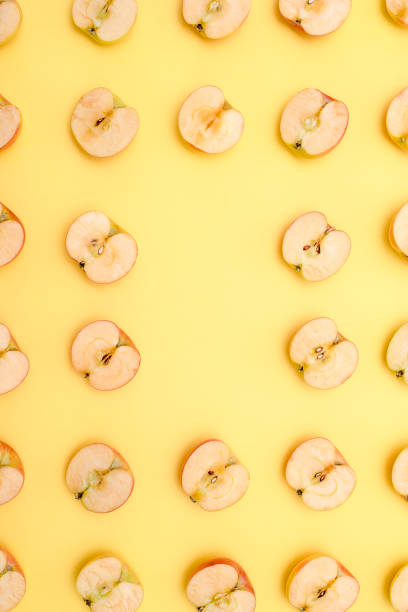 istock Background of cut in half apples on yellow background 1139605611