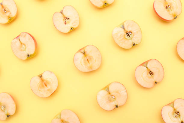 istock Background of cut in half apples on yellow background 1139605629