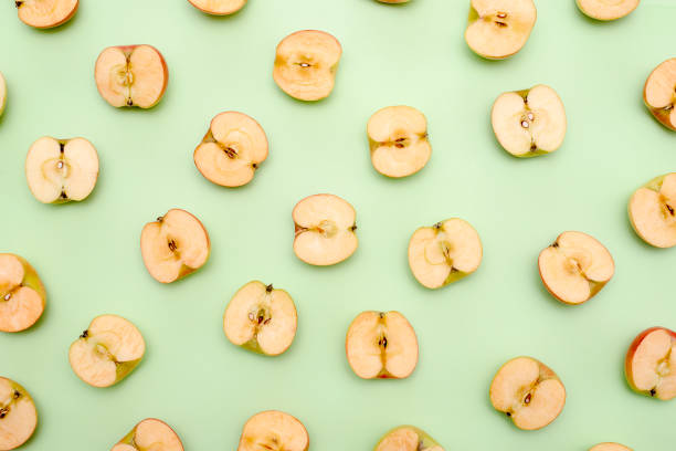 istock Background of cut in half apples on green background 1139605640