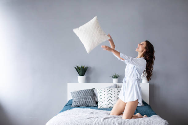 istock Happy woman having fun pillow throws enjoying funny activity on weekend at home. 1139605641