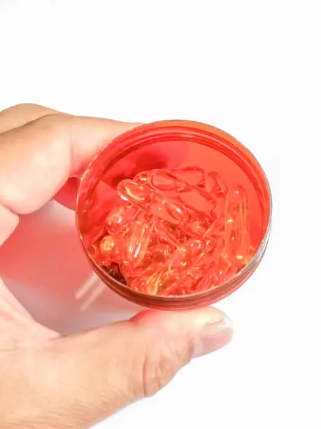 Fishoil capsule in Jar on hand on white background