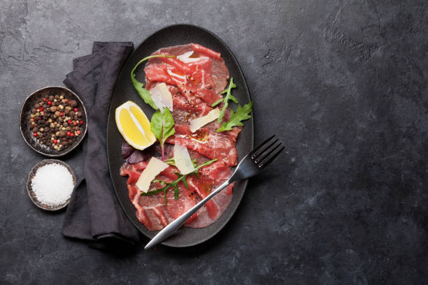 Marbled beef carpaccio Marbled beef carpaccio with arugula, lemon and parmesan cheese. Top view, flat lay with copy space carpaccio parmesan cheese beef raw stock pictures, royalty-free photos & images