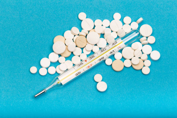 istock medical  thermometer and white pills on blue  background close up view- Image 1139612764